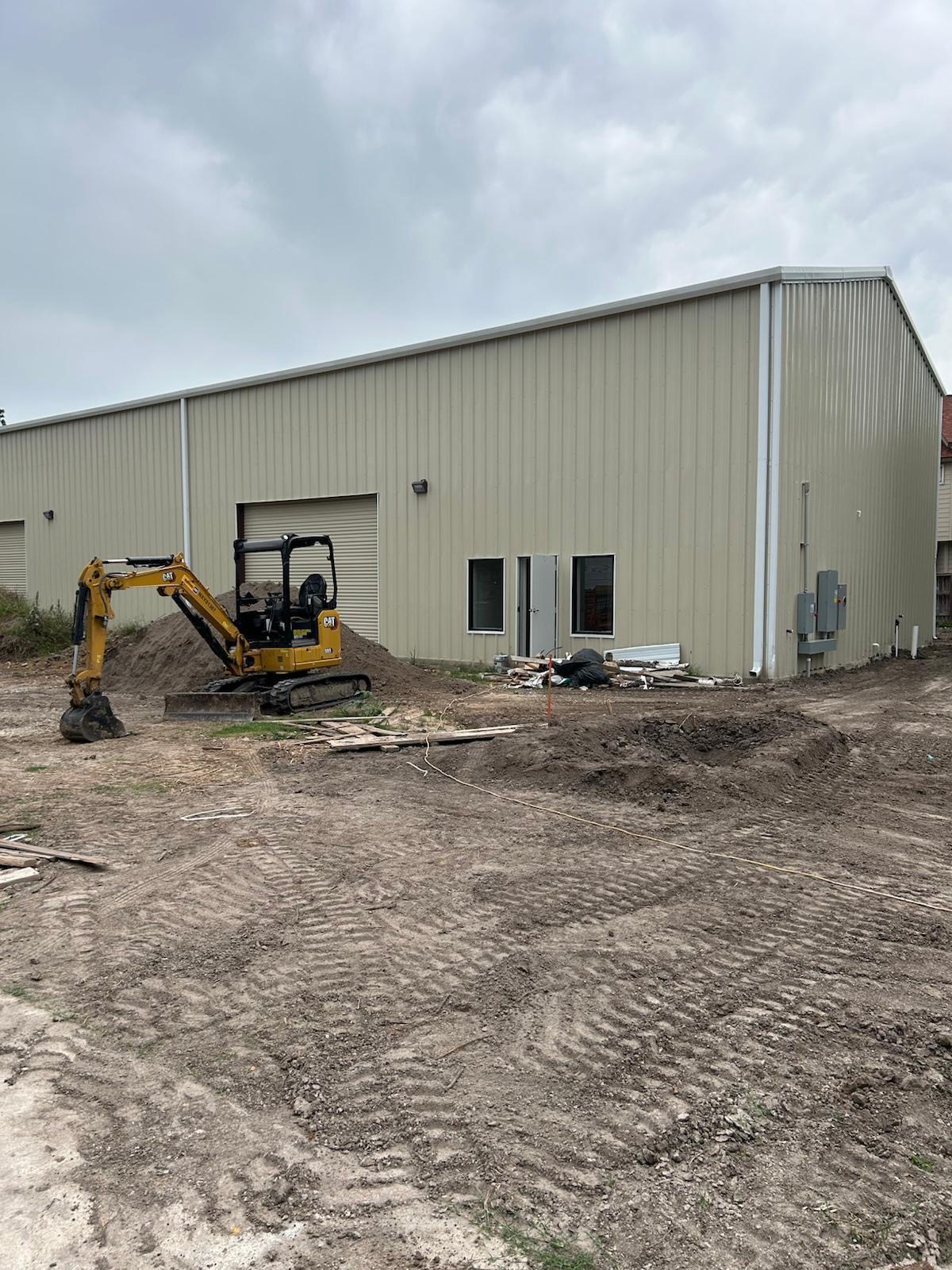 Excavator grading around warehouse